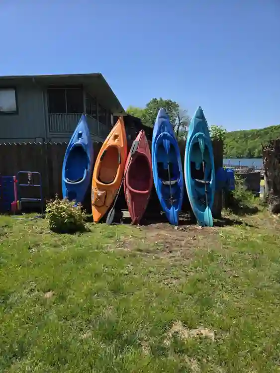 Outdoor kayak rental area at Taneycomo Resort in Branson, Missouri, with colorful kayaks lined up beside the building and lake in the background